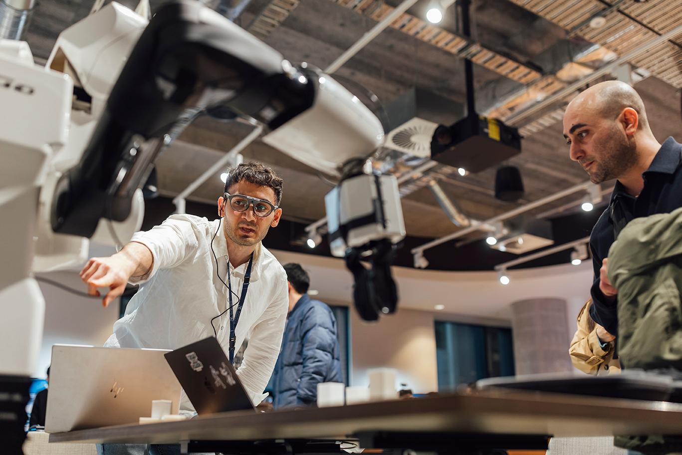 A graduate researcher demonstrates how a machine operates.