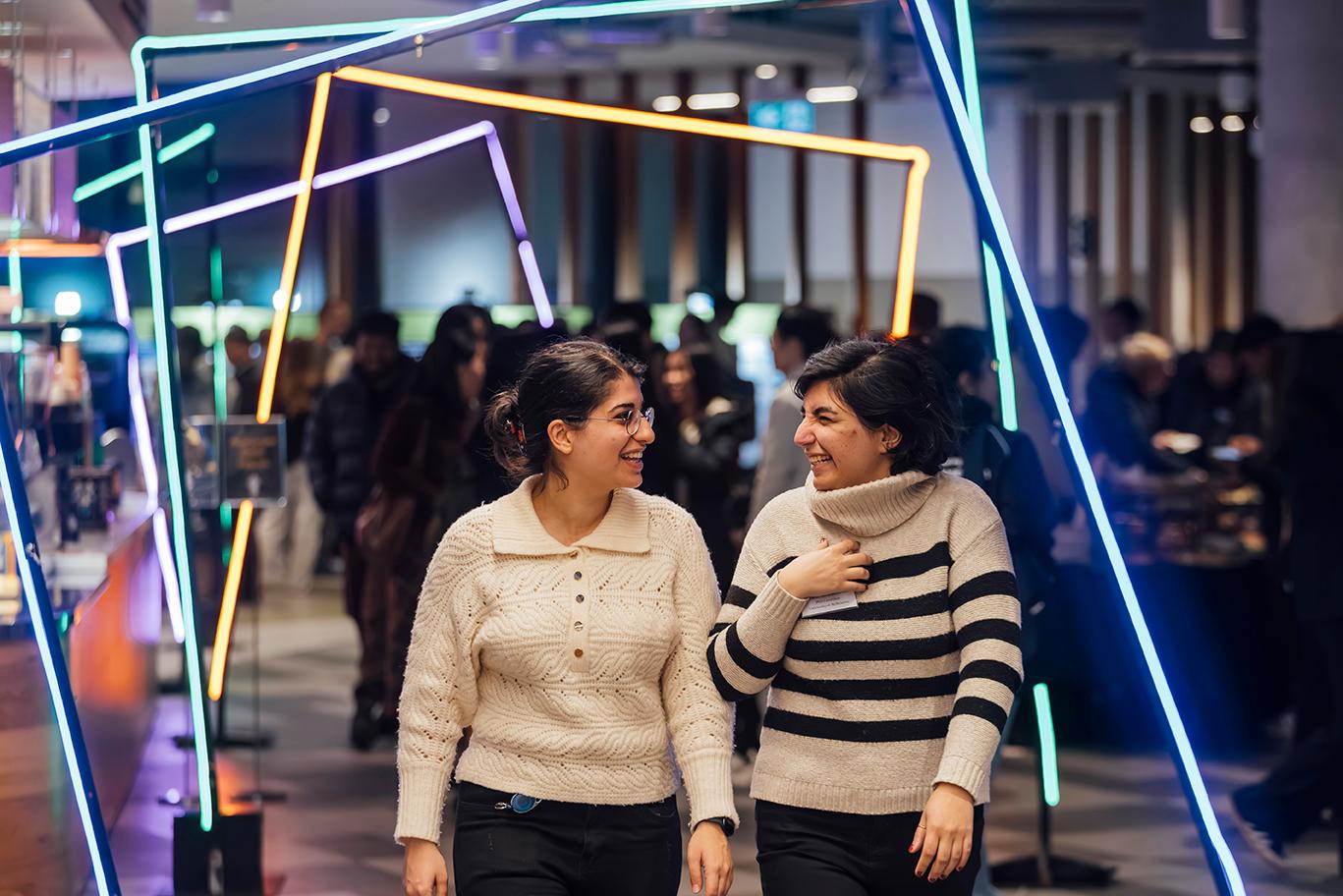 Two of smiling women are walking through the beautifully decorated event venue.