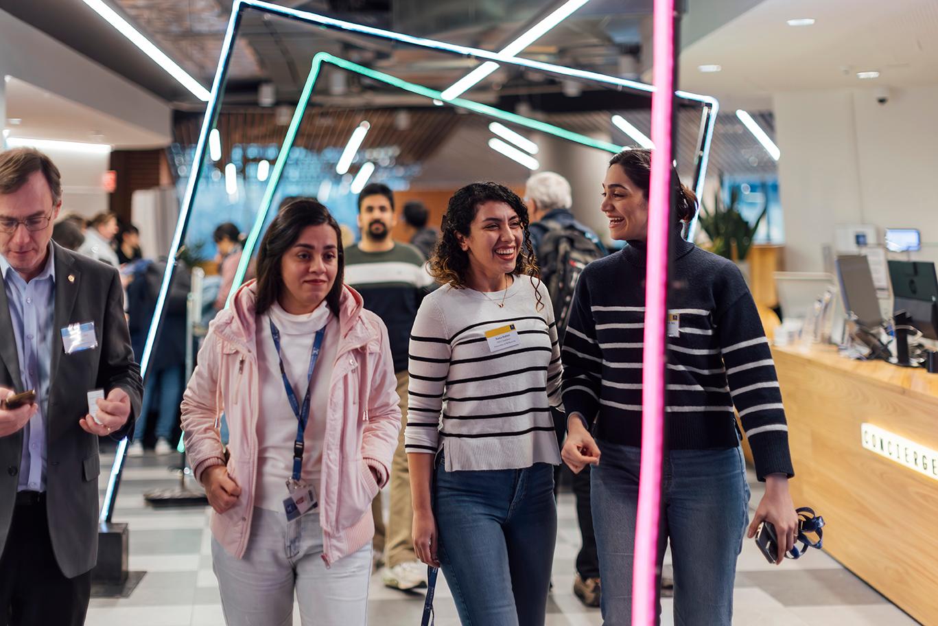 A group of smiling women are walking through the beautifully decorated event venue.